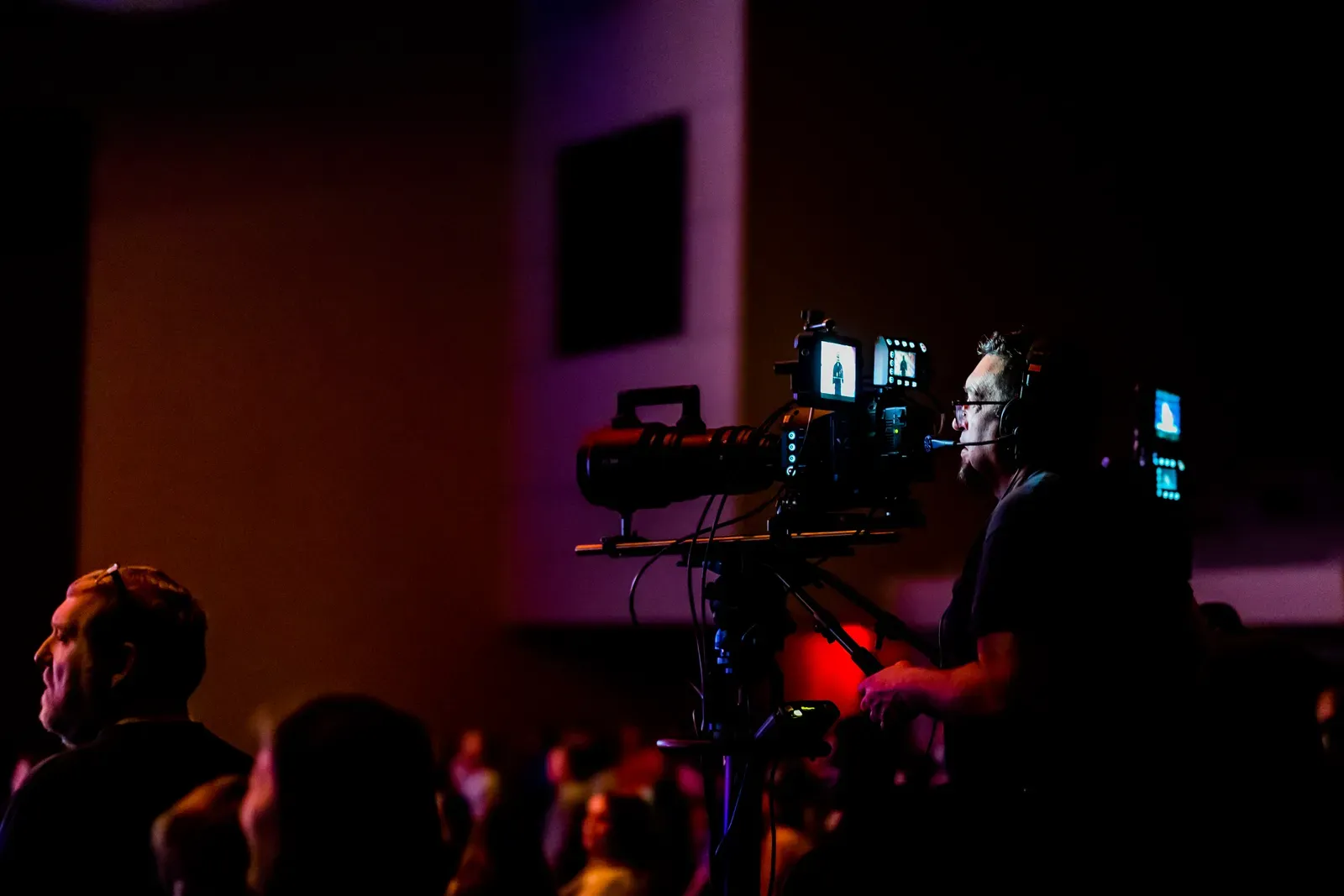 Videograf mit Kamera bei einer Live-Veranstaltung als Symbol fuer Corporate TV und Streaming