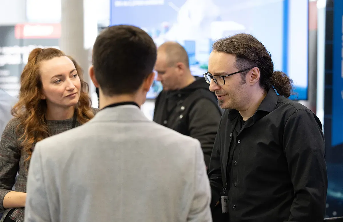 Gruppe von Teilnehmern im Gespräch am TMT-Messestand