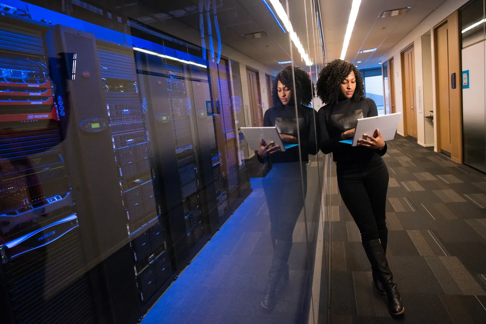 IT-Fachkraft mit Laptop vor Serverracks in einem Rechenzentrum