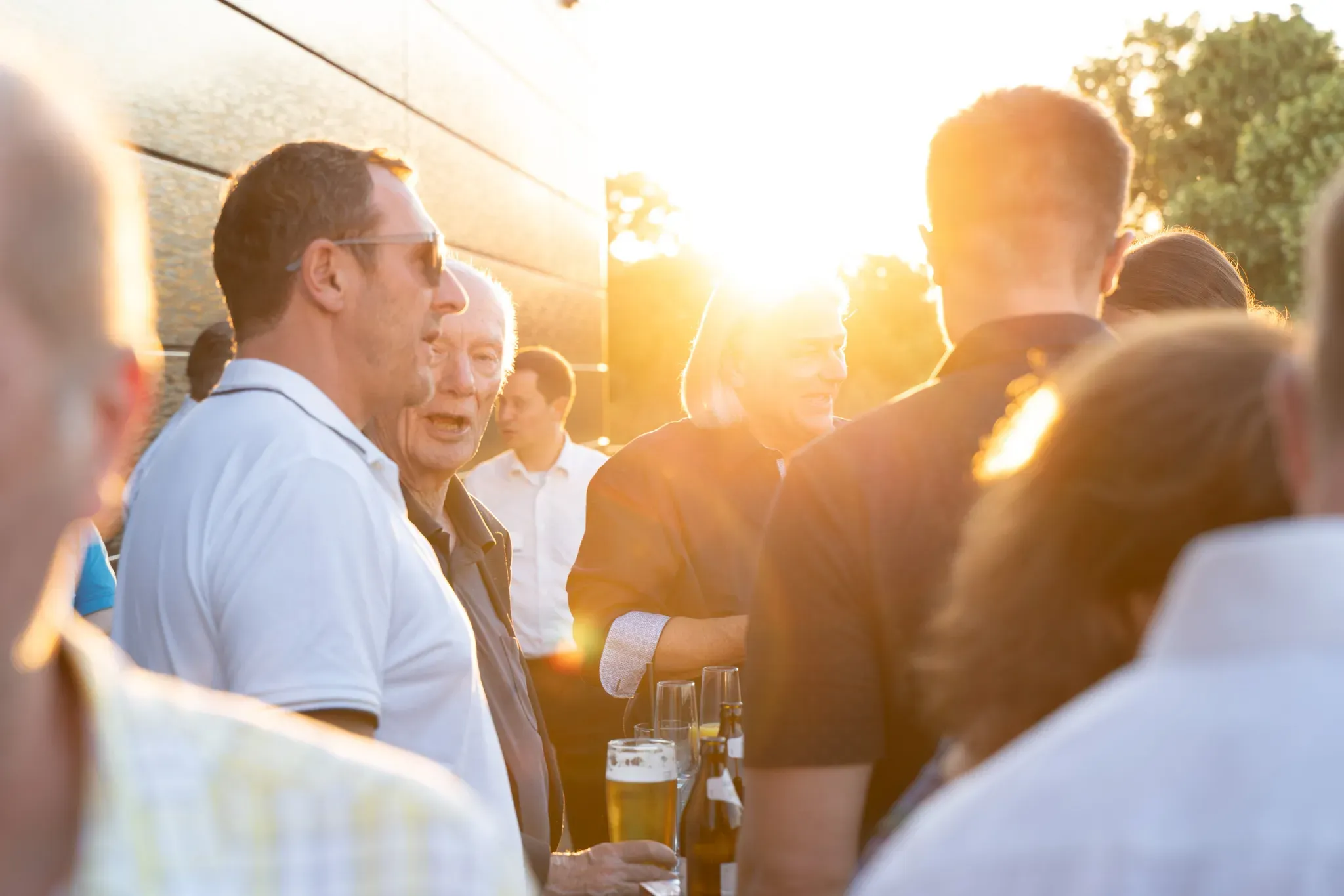 Gäste im Gespräch bei Sonnenuntergang auf der Terrasse