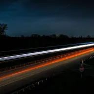 Rote und weiße Lichtspuren von Autos auf einer Straße bei Nacht