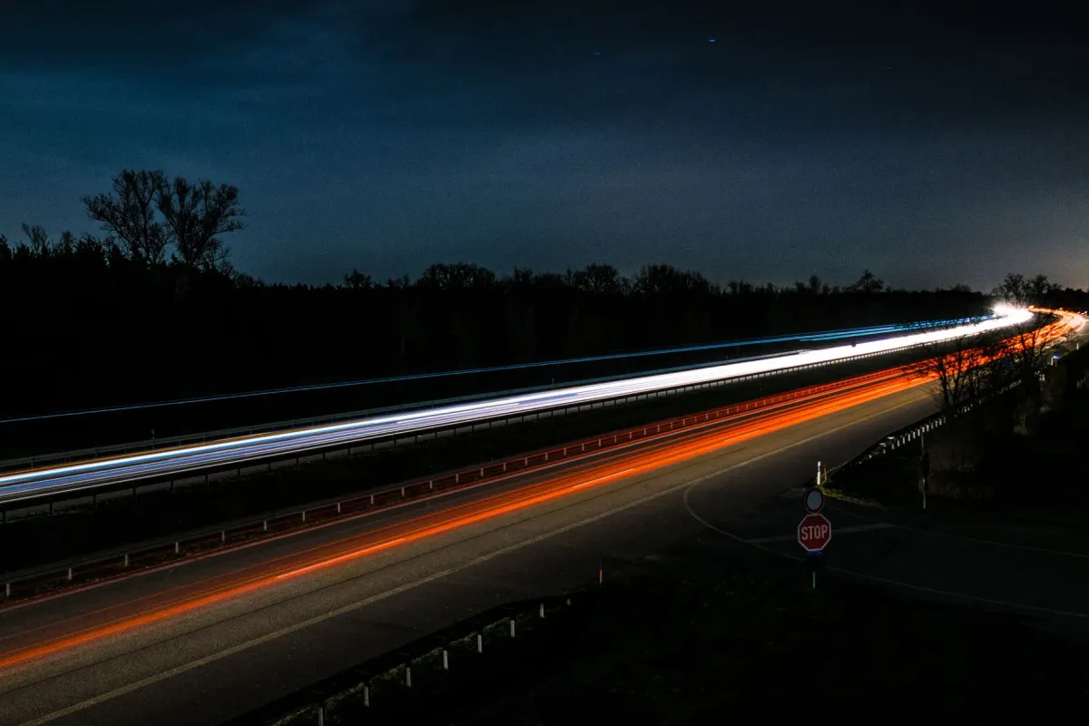 Rote und weiße Lichtspuren von Autos auf einer Straße bei Nacht