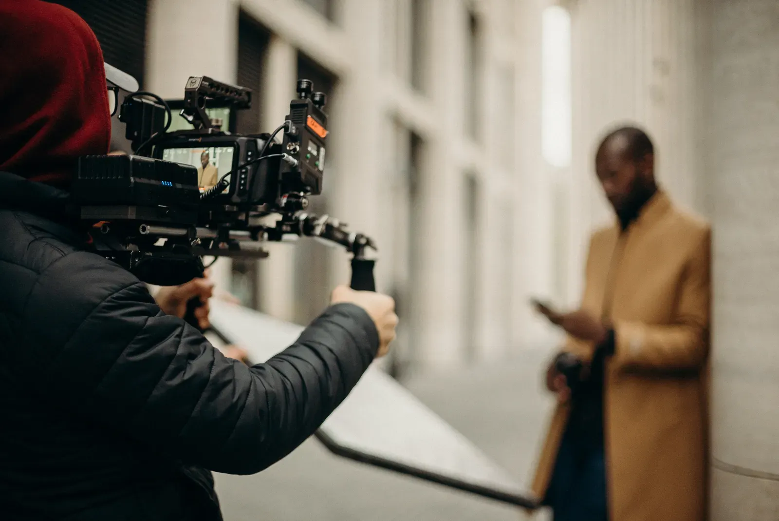 Person mit professioneller Kamera in urbaner Umgebung als Symbol fuer Videoproduktion