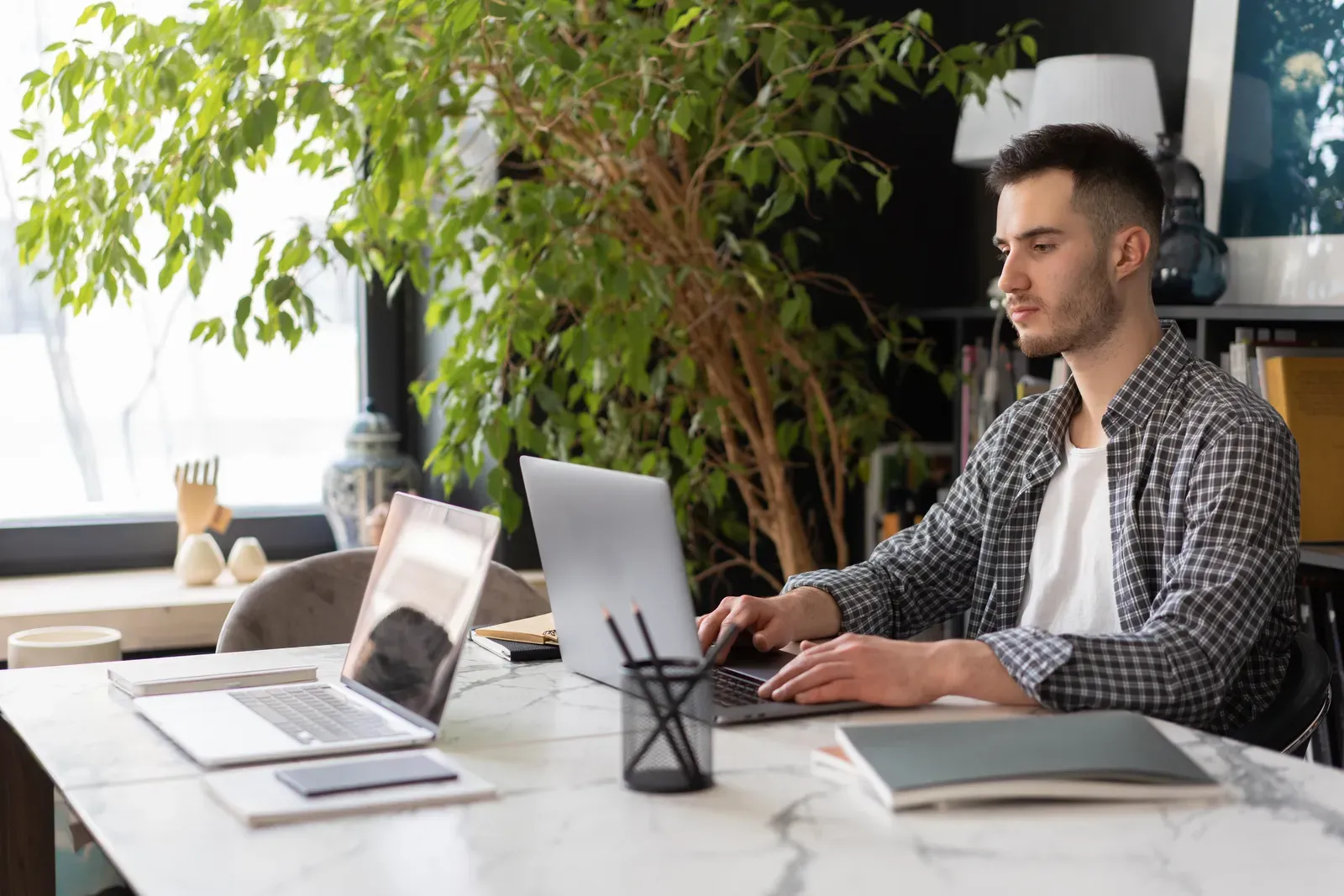 IT-Fachkraft arbeitet mit Laptop an einem aufgeraeumten Arbeitsplatz als Symbol fuer sichere Vernetzung und Connectivity