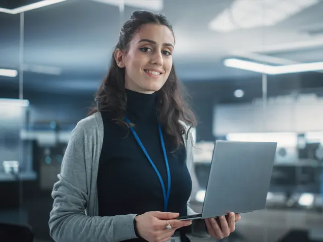 zwei Laptops und zwei Menschen am Schreibtisch machen sich Notizen